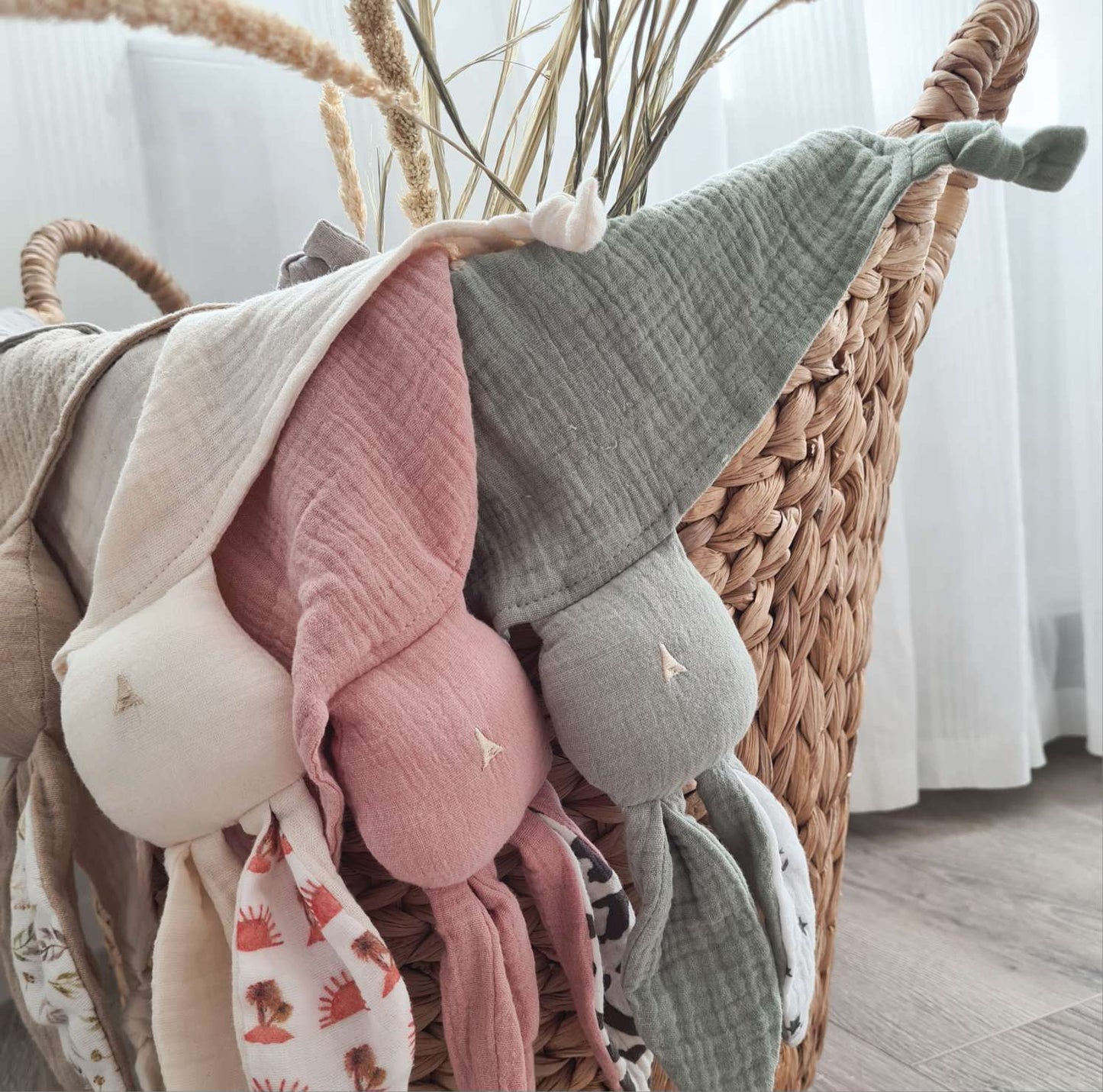 Assorted bunny baby comforters in a basket, showcasing various colours and patterns. Soft, personalised comforters for babies.