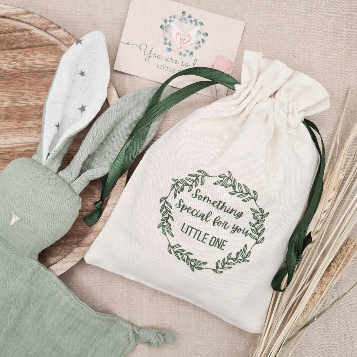 Green bunny baby comforter beside a gift bag, ready for gifting. A personalised comforter for newborns.