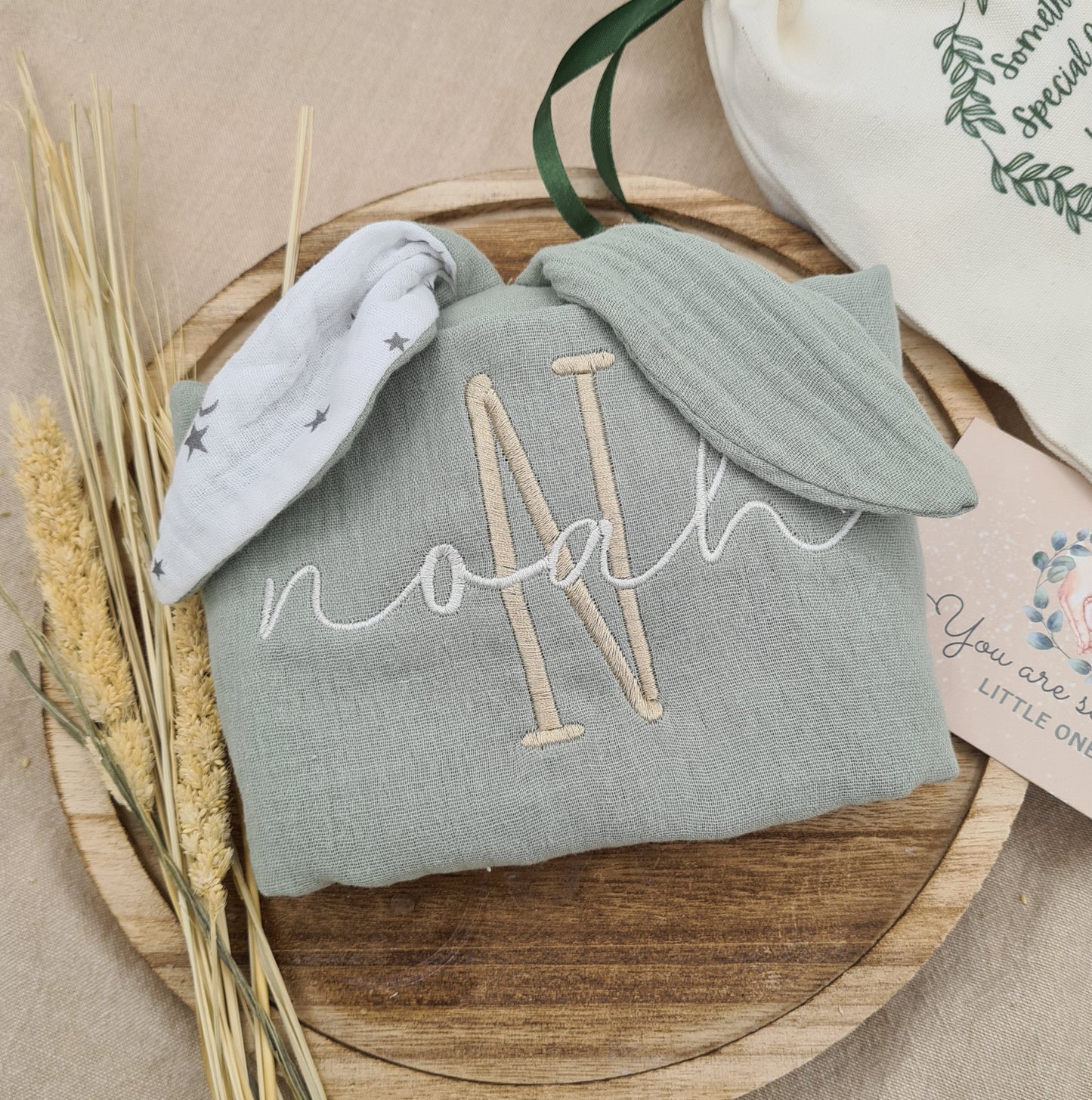 Green baby comforter with bunny ears, personalised with embroidered name 'Noah'. Made from soft cotton, perfect for babies.
