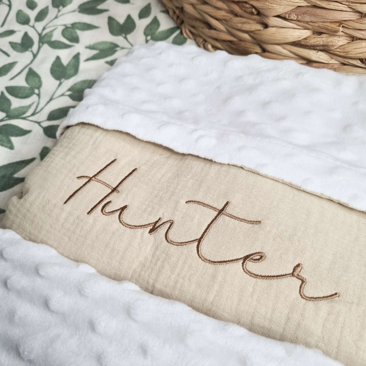 Close-up view of beige personalised baby blanket with embroidered name 'Hunter' and soft white plush trim.