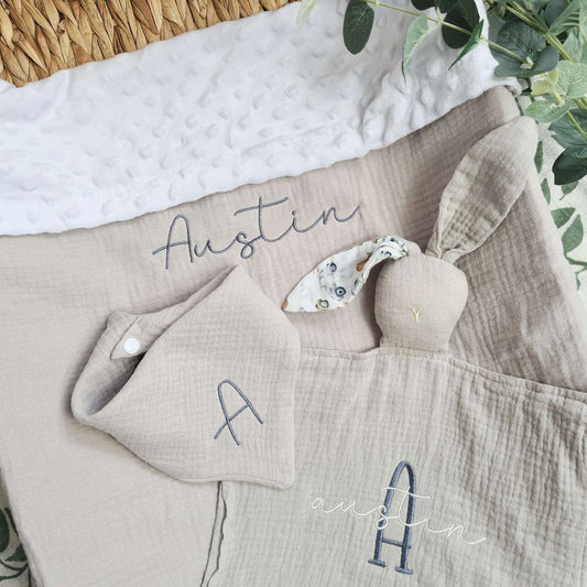 Personalised baby blanket gift set with embroidered name 'Austin', including a soft muslin blanket, bunny comforter, and bib. Made from organic cotton.